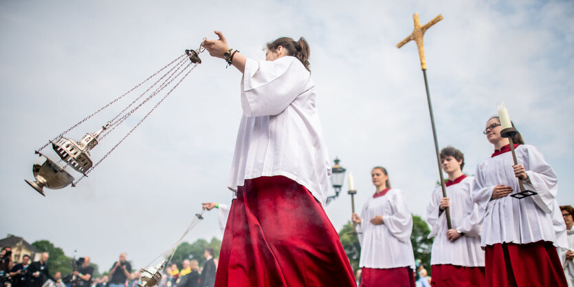 Messdiener tragen ein Weihrauchfass und ein Kreuz