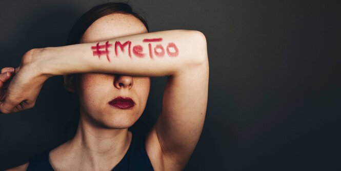 Eine Frau hebt den linken Arm vor die Augen, darauf zu sehen ist in roter Schrift #MeToo