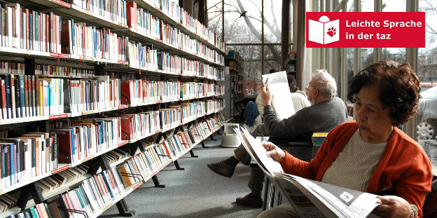 Zwei Menschen sitzen in einer Bücherei und lesen, neben ihnen steht ein Bücherregal