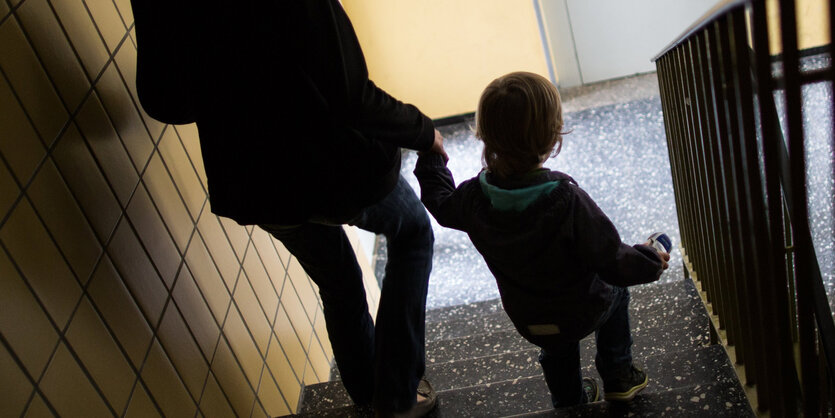 Eine Frau führt ein Kind eine Treppe hinunter.