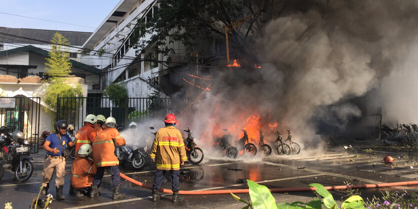 Feuerwehrleute stehtn vor einer stark rauchenden Brandstelle