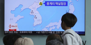 Menschen blicken auf einen Bildschirm, der Korea zeigt