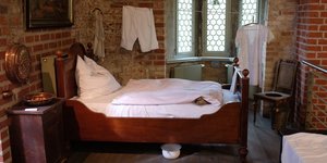 Ein Zimmer mit einem vielleicht 100 Jahre alten Bett und einem Nachtopf darunter