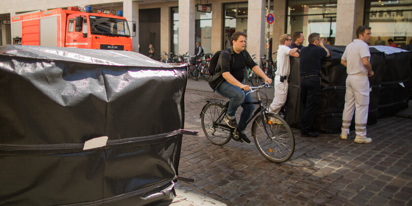 Blöcke aus Beton sperren eine Straße für Autos und Lkw ab, eine Radfahrerin kommt aber durch