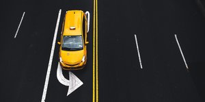Aufsicht auf ein gelebes Auto auf einer Straßenspur mit Pfeil nach links