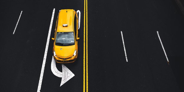 Aufsicht auf ein gelebes Auto auf einer Straßenspur mit Pfeil nach links