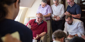 Peter Altmaier in einem Flugzeug, umringt von schreibenden Männern