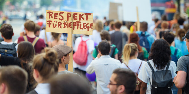 Eine Menschenmenge, aus der ein Schild mit der Aufschrfit „Respekt für Pflege“ in die Höhe ragt