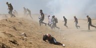 Menschen rennen eine staubige Sanddüne herauf