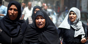 Drei Frauen trauern auf einer Beerdigung
