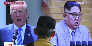 Donald Trump und Kim Jong Un auf einem Bildschirm während einer Nachrichtensendung. Davor ein Zuschauer