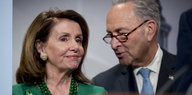 Nancy Pelosi und Chuck Schumer lachen an einem Pult