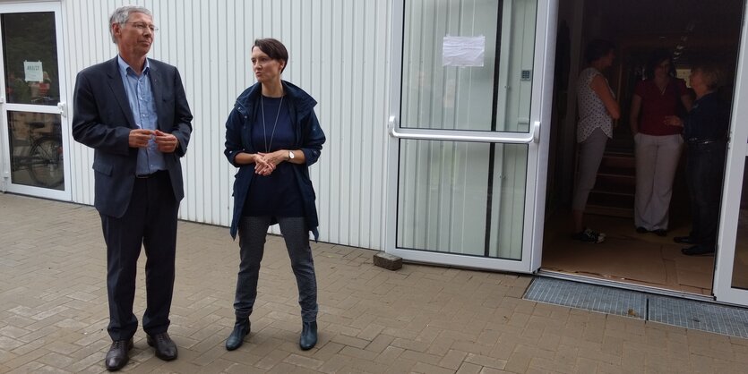 Ein Mann und eine Frau stehen vor einem Wohn-Container mit geöffneter Tür.