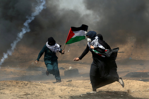 Zwei Demonstrantinnen mit Palästina-Fahne fliehen vor dem Tränengas des israelischen Militärs