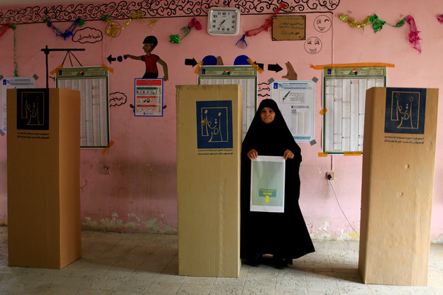 Eine Frau steht in einer irakischen Wahlstube