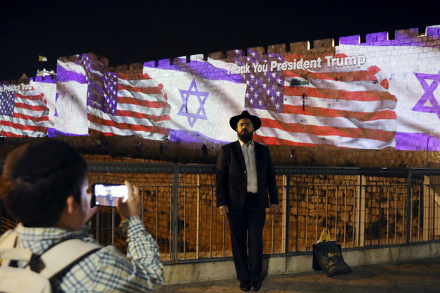 Ein Mann lässt sich vor der Stadtmauer in Jerusalem fotografieren, an die die amerikanische und die israelische Flagge projeziert werden