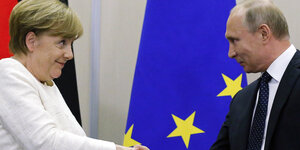 Merkel und Putin geben sich die Hand und schauen sich an