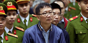 Der vietnamesische Geschäftsmann, Trinh Xuan Than, steht neben sehr vielen vietnamesischn Staatsbediensteten