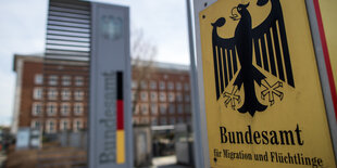 Ein gelbes Schild mit einem Bundesadler an einem Tor