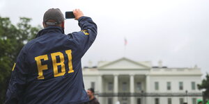 ein Mann mit einer FBI-Jacke macht ein Foto vom Weißen Haus