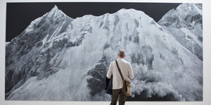 Ein Betrachter steht vor einem Bild, dass einen weißen Berggipfel zeigt