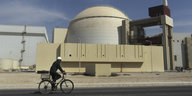 Ein Mann auf einem Fahrrad fährt an einem Atomkraftwerk vorbei