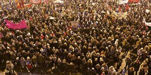 Viele Männer und Frauen stehen in Mänteln auf einem Platz in Oslo