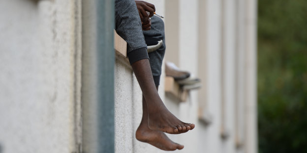 Beine eines Asylbewerbers, der auf dem Fensterbrett sitzt
