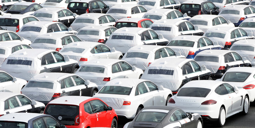 Viele, teils mit Planen überzogene Autos stehen auf einem riesigen Werksparkplatz