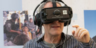 Der Regisseur Dani Levy hat eine schwarze Virtual Reality Brille und Kopfhörer auf