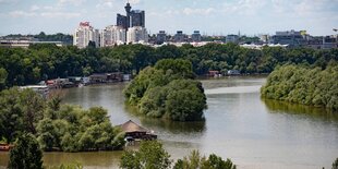 Über eine Flusslandschaft hinweg ist ein Hochhauskomplex sichtbar