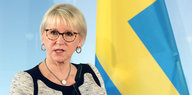 Margot Wallström neben einer schwedischen Fahne