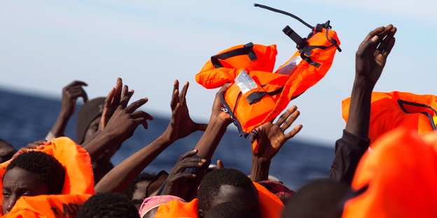 Flüchtlinge auf einem Boot fangen Rettungswesten