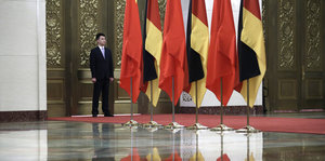 Ein Mann steht zwischen deutschen und chinesischen Flaggen