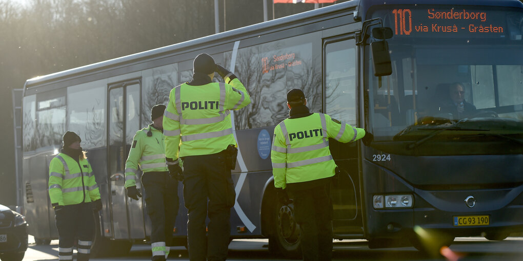 Vier dänische Polizisten halten einen Bus auf