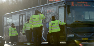 Vier dänische Polizisten halten einen Bus auf