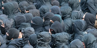 eine Menge Menschen in schwarzer Kleidung, die Gesichter durch Kapuzen und Schals oder Tücher verhüllt