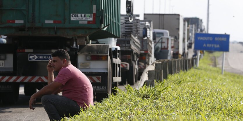 Viele LKW und ein sitzender Fernfahrer am Straßenrand