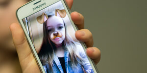 Auf einem Handy sieht man ein Mädchen mit Hundeohren und -nase