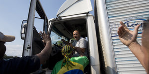 wütende Streikende reden auf einen LKW-Fahrer in seinem Truck ein