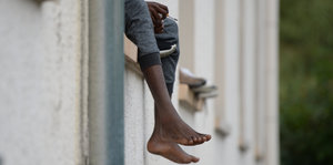 Ein Asylbewerber sitzt auf dem Fensterbrett einer Asylunterkunft
