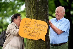 Ein Mann und eine Frau befestigen ein Protestschild an einem Baum Ein Mann und eine Frau befestigen ein Protestschild an einem Baum