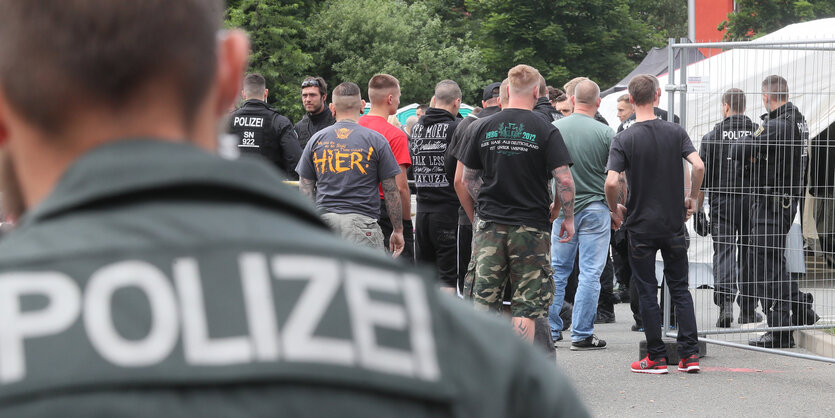 Ein Polizist beobachtet eine Gruppe Neonazis