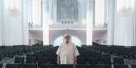 Mann mit weißem Hemb steht in einer Kirche