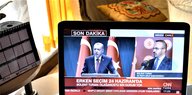 Ein Fernsehbildschirm - darauf zu sehen sind zwei Männer, einer davon ist Präsident Erdogan