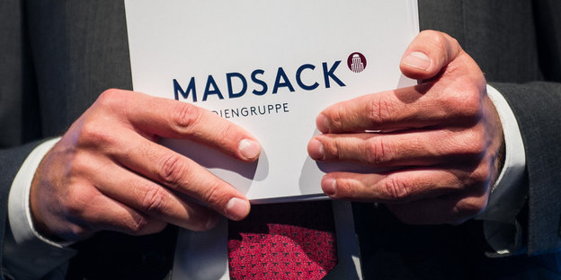 Ein Mann Moderationskarten mit der Aufschrift "Madsack" in den Händen