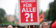 Ein Frau hält ein Schild mit der Aufschrift "Wohnen für Alle?!" hoch.