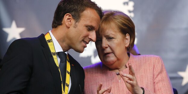 Macron und Merkel stecken die Köpfe zusammen.