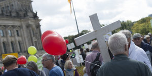 Menschen vor dem Reichstag, einer hält ein weißes Kreuz