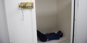 Ein Mann liegt in einer Zelle der Gefangenensammelstelle